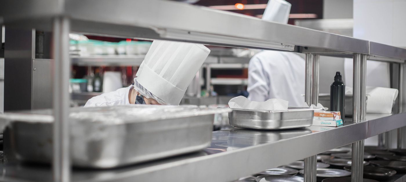 Chefs working in a stainless steel commercial kitchen — Malaysian restaurants must control pests under the Food Hygiene Regulations 2009