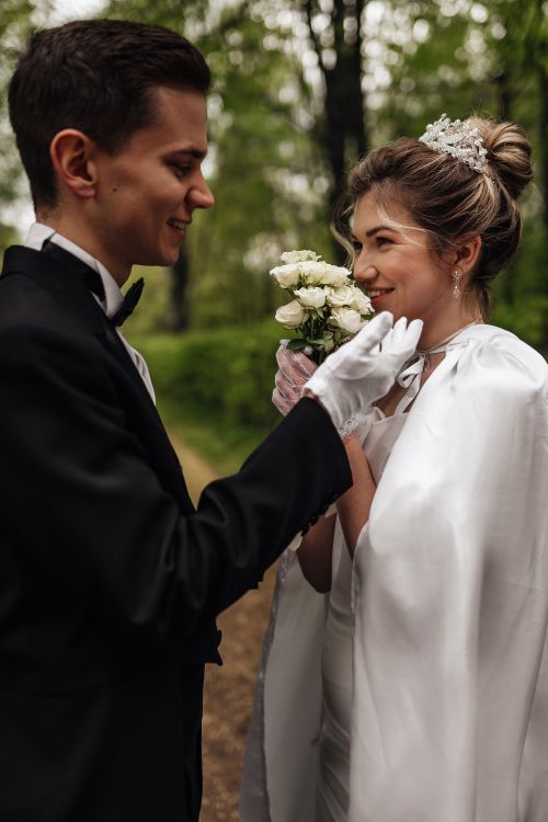 Free Bride and groom smiling lovingly in a lush green outdoor setting, perfect wedding moment. Stock Photo