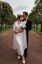 Man in Black Suit Kissing Woman in White Wedding Dress on Brown Field