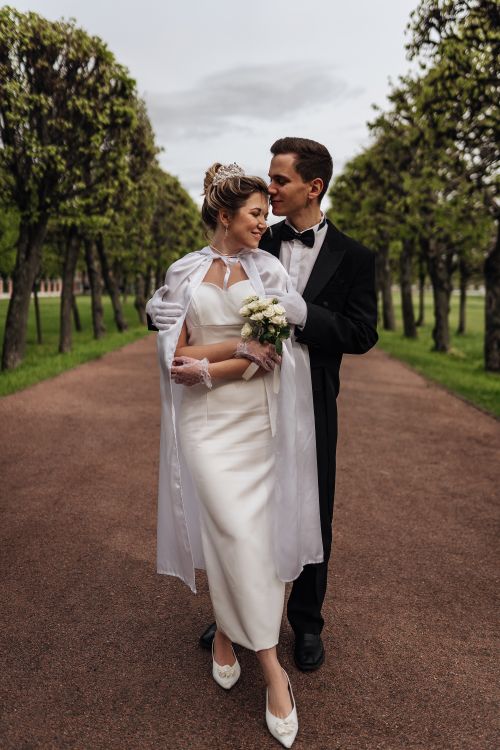 Free Bride and groom embracing in a scenic outdoor park with lush greenery, capturing a romantic wedding moment. Stock Photo