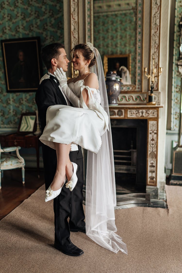 Groom Carrying A Bride In A White Dress And Veil