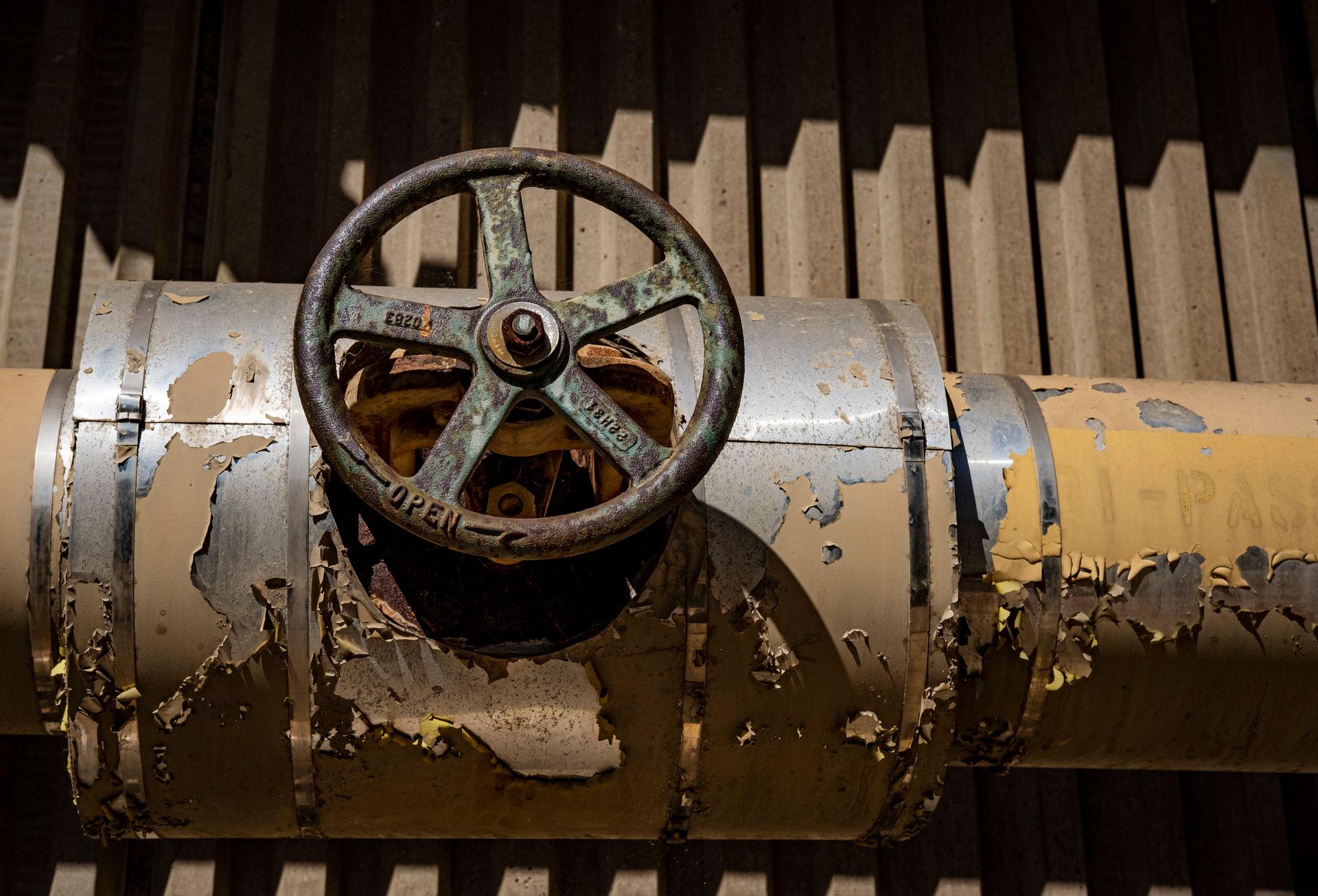 Close-up of a rusty industrial valve on a peeling weathered pipe.