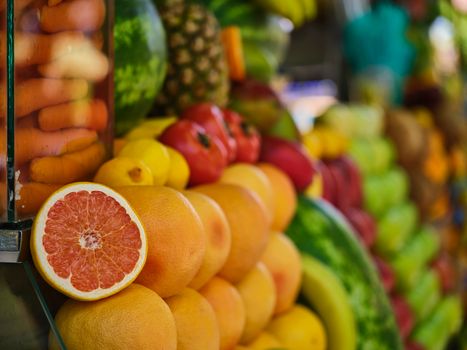 A colorful arrangement of fresh fruits including grapefruit, oranges, and pineapples in a market setting.