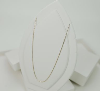 Minimalist gold necklace showcased on a white display stand, perfect for jewelry lovers.