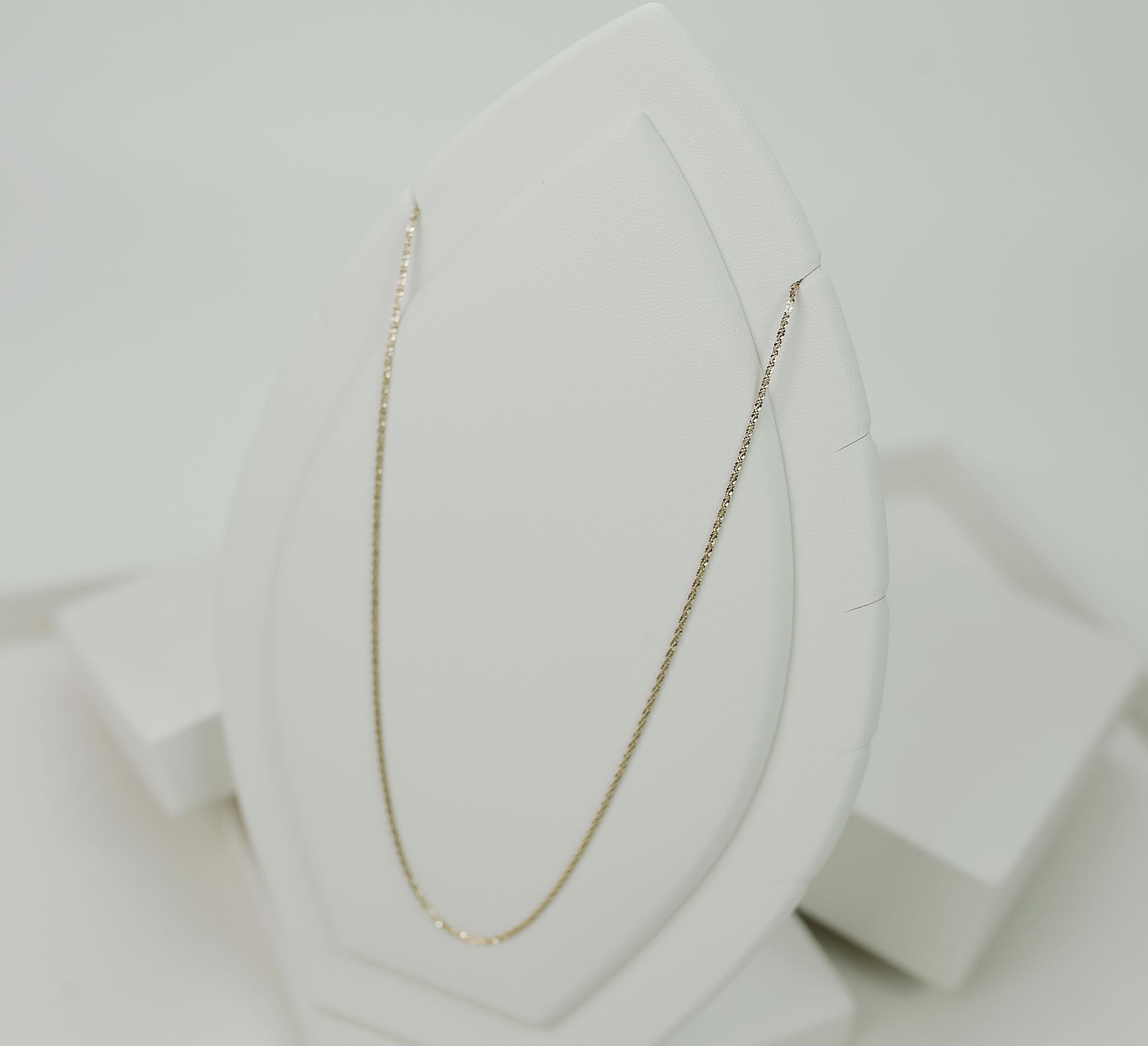 Minimalist gold necklace showcased on a white display stand, perfect for jewelry lovers.