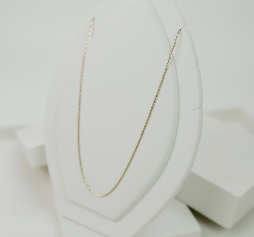 Free Close-up of a delicate gold necklace displayed elegantly on a white stand, perfect for fashion and jewelry lovers. Stock Photo