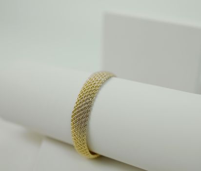 Close-up of a gold bracelet elegantly displayed against a minimalist backdrop, perfect for fashion and jewelry showcases.