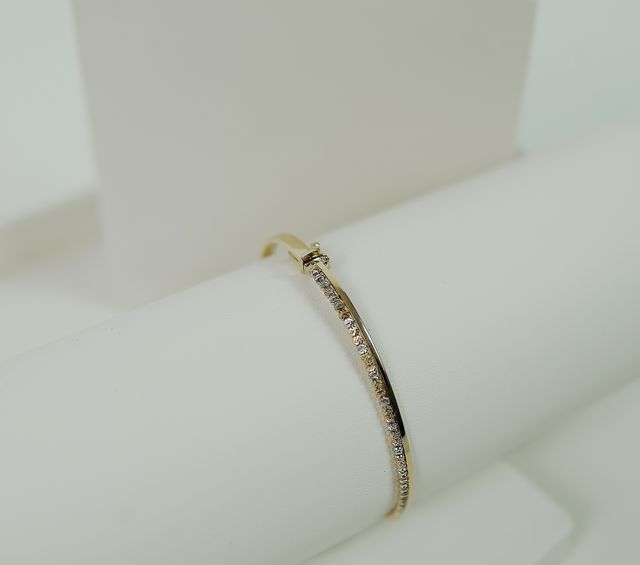 Gold bracelet set with diamonds on a display stand