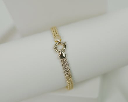 Close-up of a luxurious gold bracelet on a white background, perfect for elegant jewelry promotion.