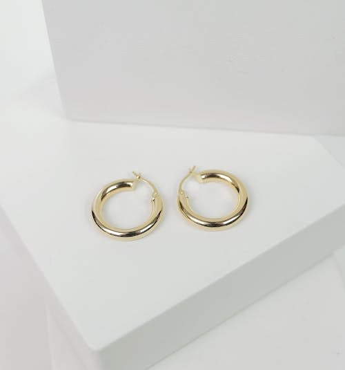 Free Close-Up Shot of Gold Earrings on White Surface Stock Photo