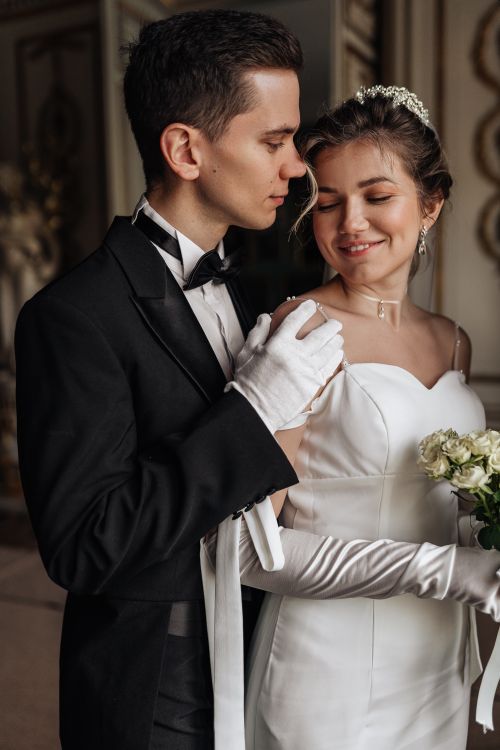 Free A joyful wedding couple embracing in an elegant indoor setting, wearing a gown and tuxedo. Stock Photo