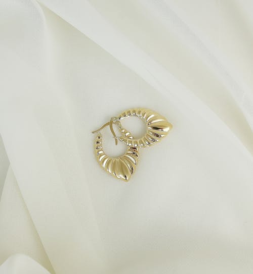 A Pair of Gold Earrings on a White Fabric