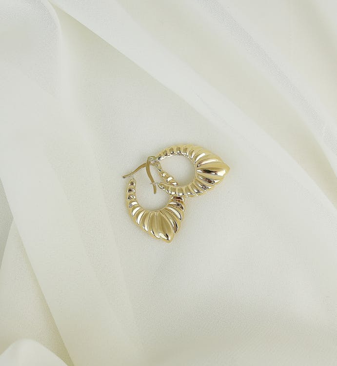 A Pair of Gold Earrings on a White Fabric