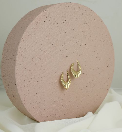 Free A pair of stylish gold earrings elegantly presented on a minimalist circular display. Stock Photo