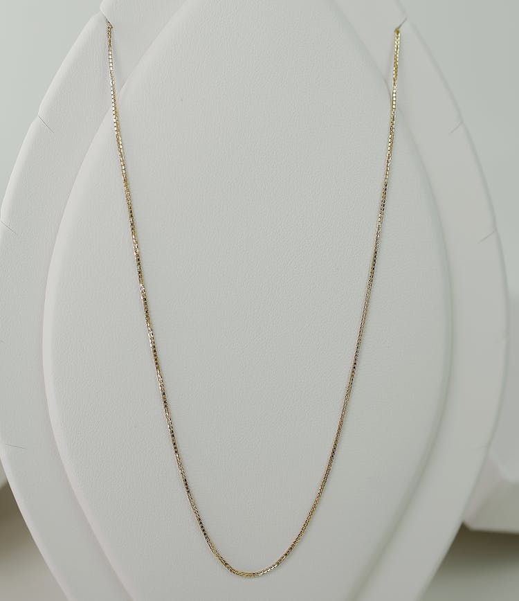 A Gold Necklace On White Necklace Holder