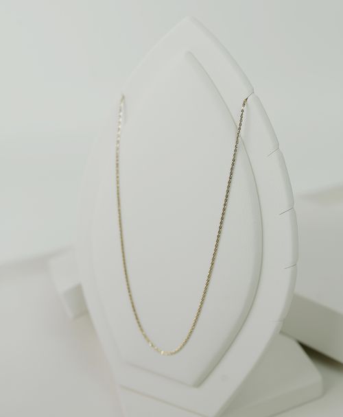 Free Simple yet luxurious gold necklace elegantly displayed on a white stand, perfect for showcasing elegance. Stock Photo