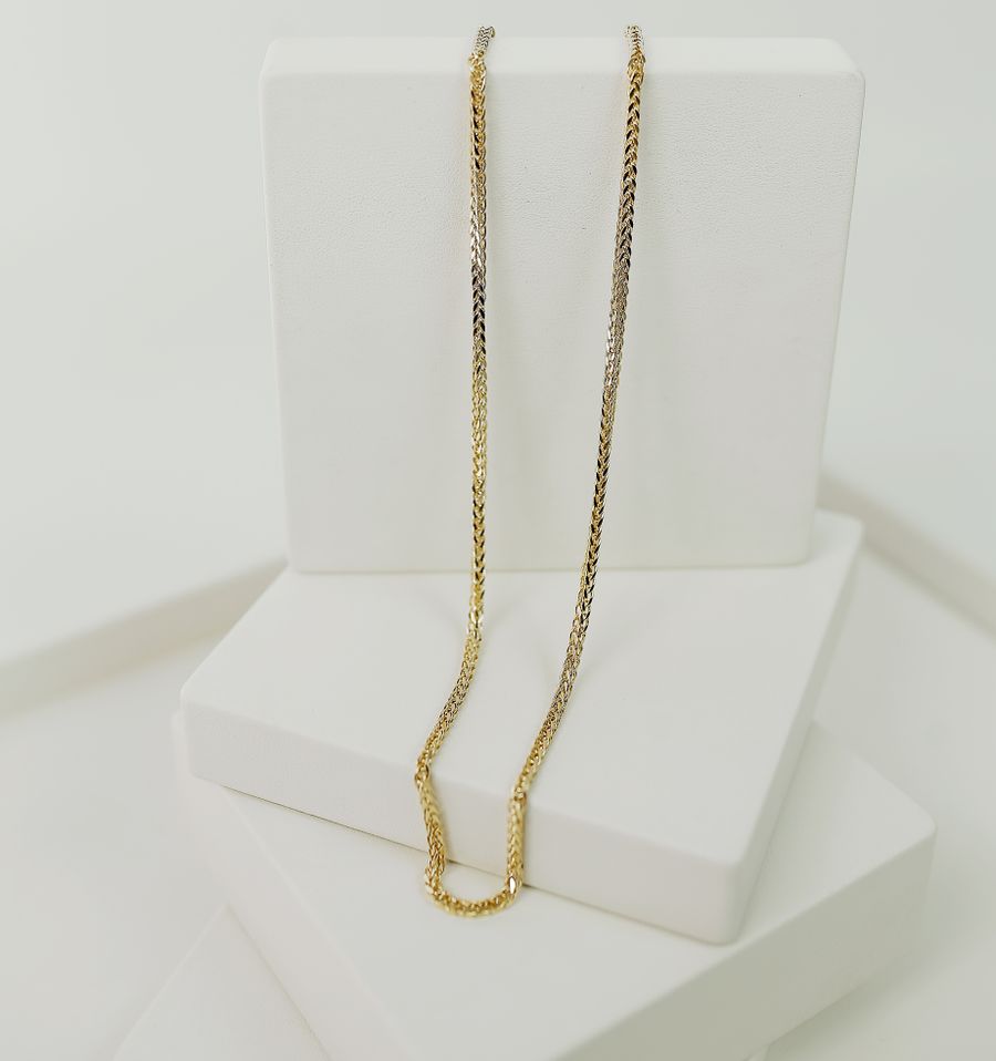 Gold necklace displayed on white platforms