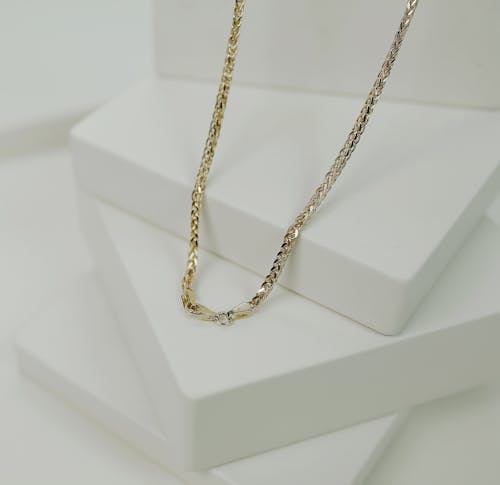 Free Gold Necklace on a White Surface in Close-up Photography Stock Photo