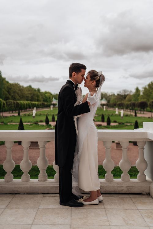 Free Bride and groom in a loving embrace on a terrace overlooking a lush garden. Stock Photo