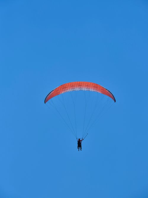 Free A solitary paraglider soars through a vivid blue sky with ample copy space. Stock Photo