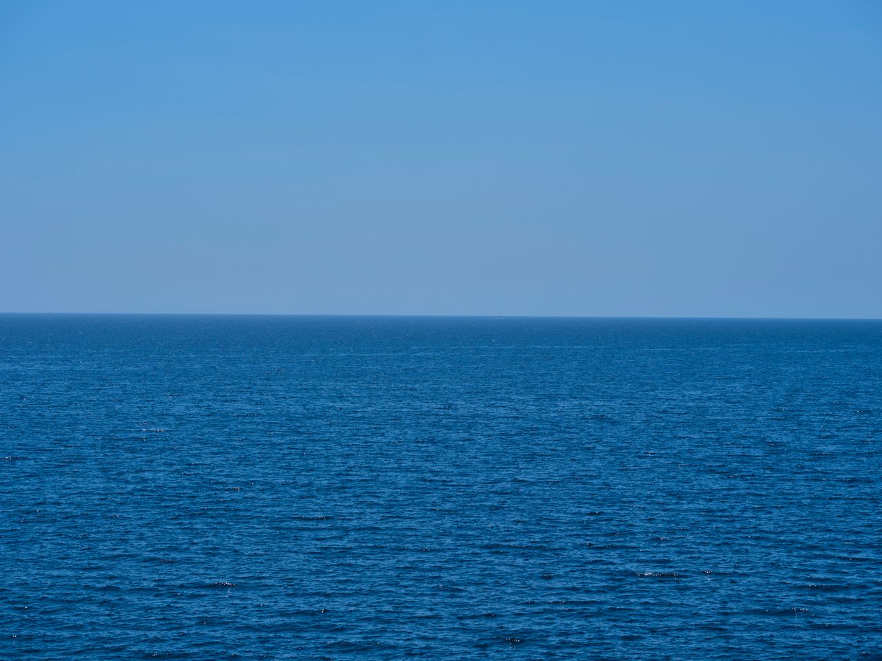 a tranquil seascape with endless blue ocean meeting the clear sky capt