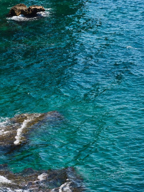 Free A stunning view of turquoise waves crashing around coastal rocks. Stock Photo
