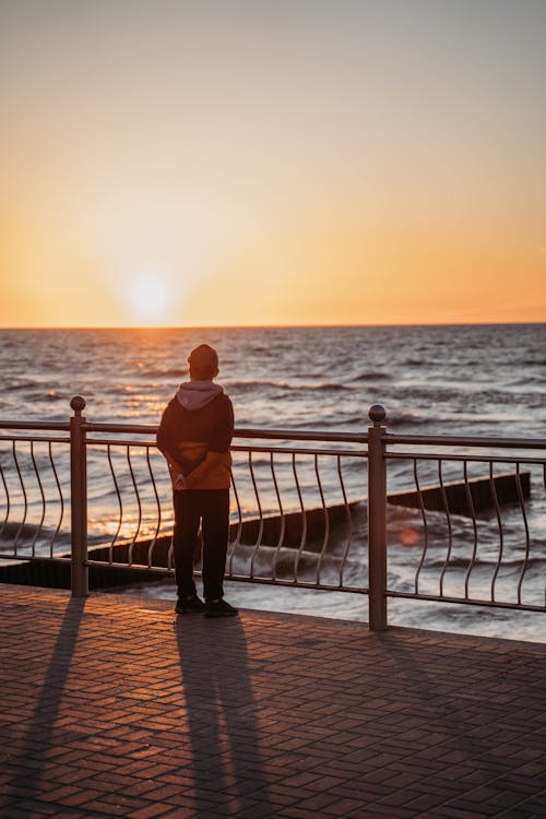 Free Person in Hoodie Jacket Standing Near Metal Railing  Stock Photo