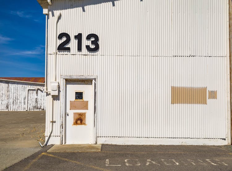 White Wooden Door On Corrugated Metal Wall Of A Building