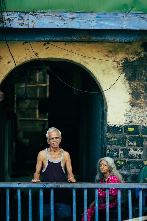Free Charming portrait of an elderly couple smiling and sitting in an alleyway in Mumbai, India. Stock Photo