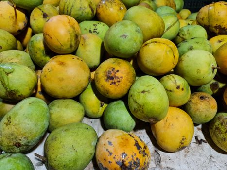 A vibrant pile of fresh, organic mangos on display in a market setting.