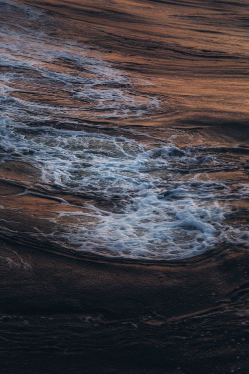 Free Captivating ocean waves creating foam under a warm sunset light, showcasing nature's beauty. Stock Photo