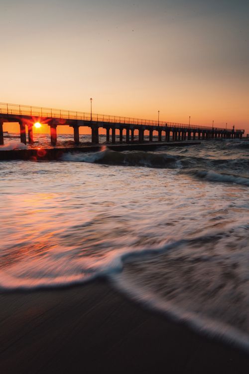 Free Breathtaking view of a sunrise over the ocean with a pier in the background, conveying tranquility. Stock Photo