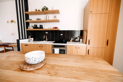 Free A contemporary kitchen featuring wooden cabinets, a black backsplash, and a minimalist design style. Stock Photo