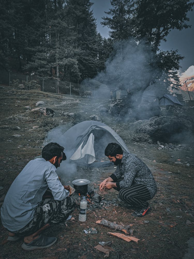 Men Cooking Outdoors Beside A Tent 