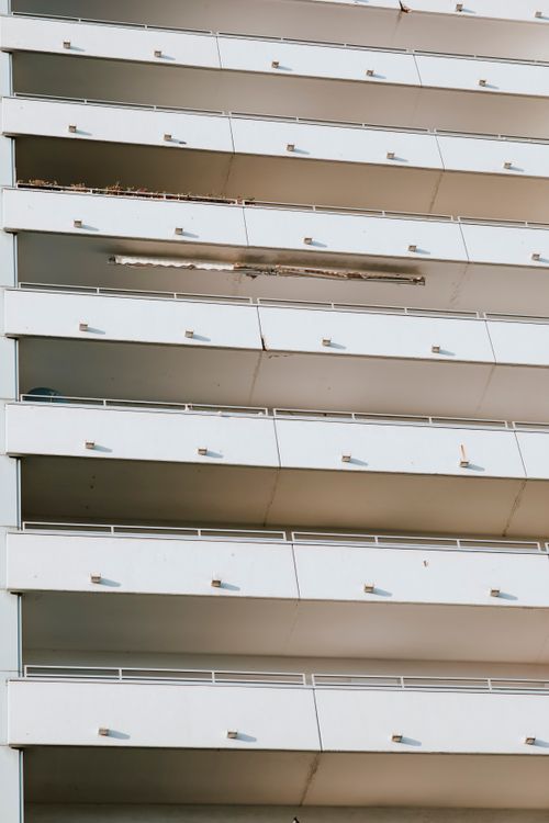 Free Detailed view of a modern high-rise building facade with sequential balconies and sunny lighting. Stock Photo