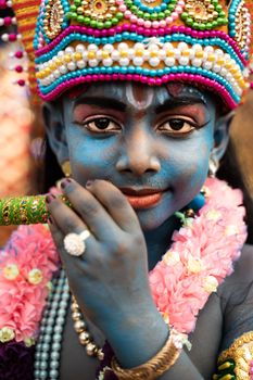 A child in vibrant attire embodies Lord Krishna at a traditional cultural festival in Thiruchendur.