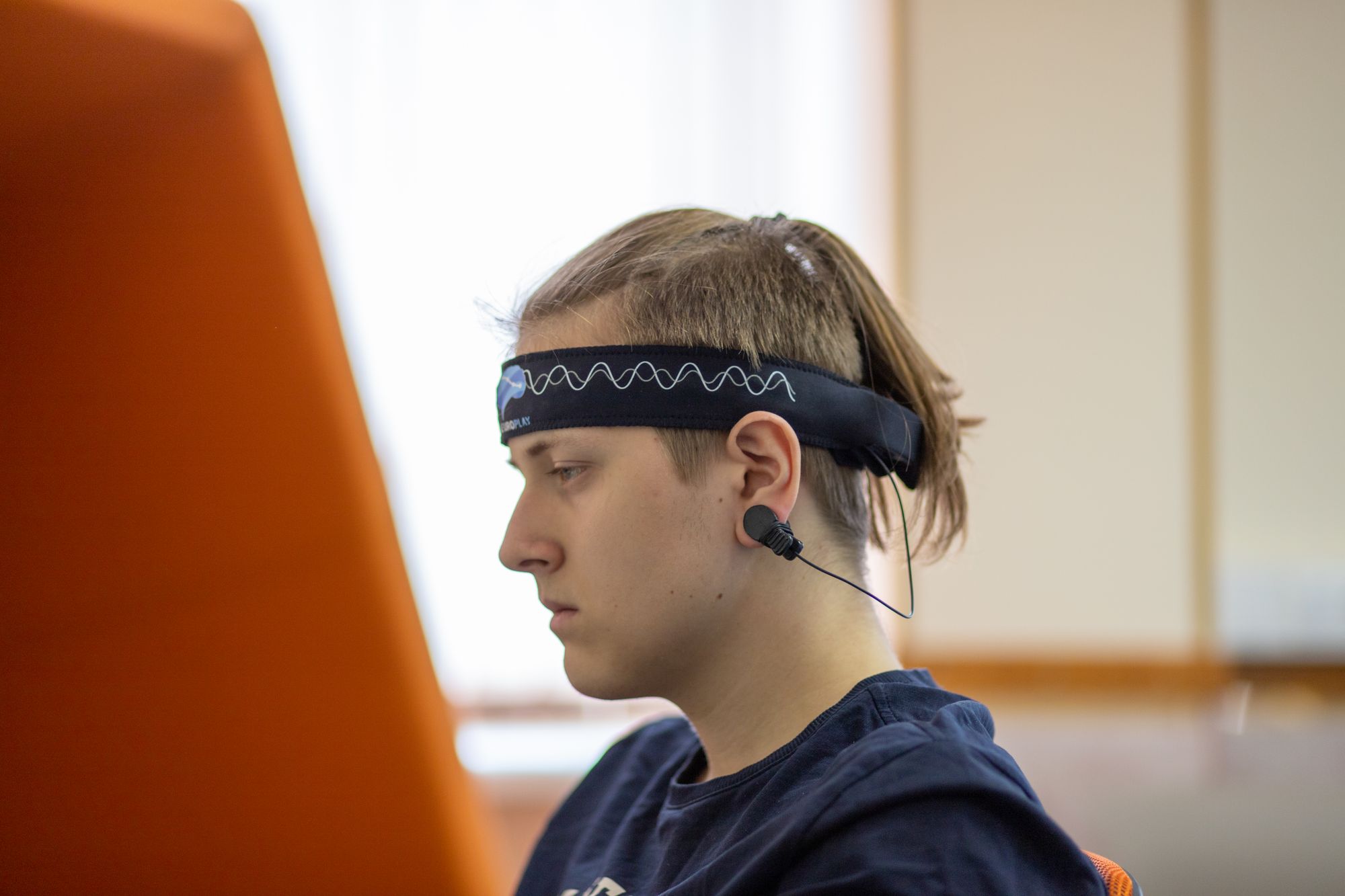 A young man using a headband EEG device while focused on his studies indoors.