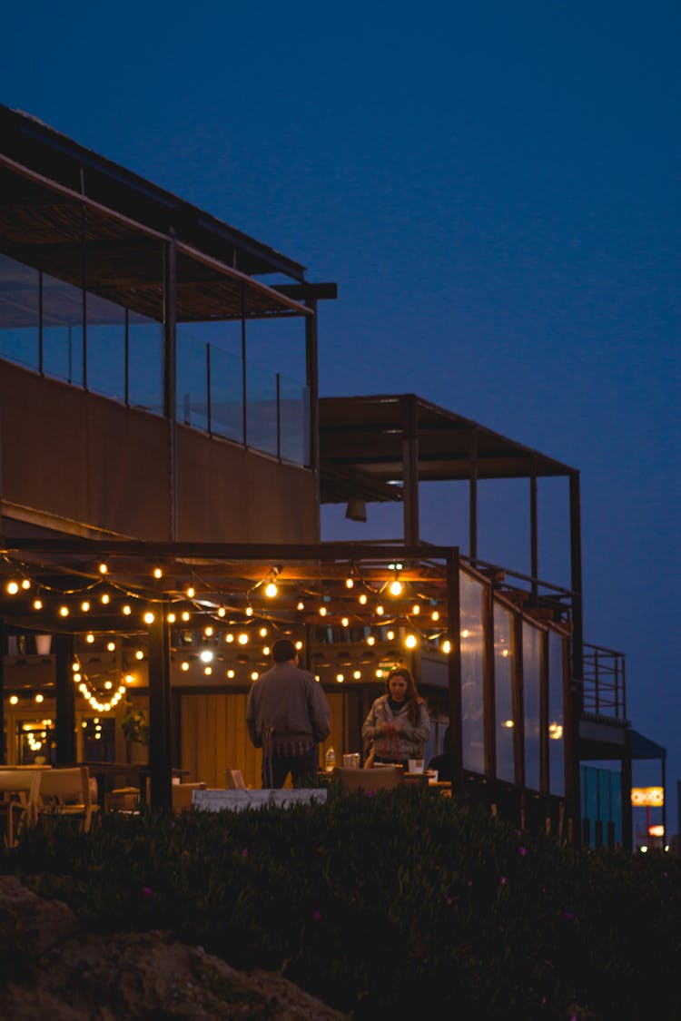 Man And Woman In Front Of Illuminated Hotel