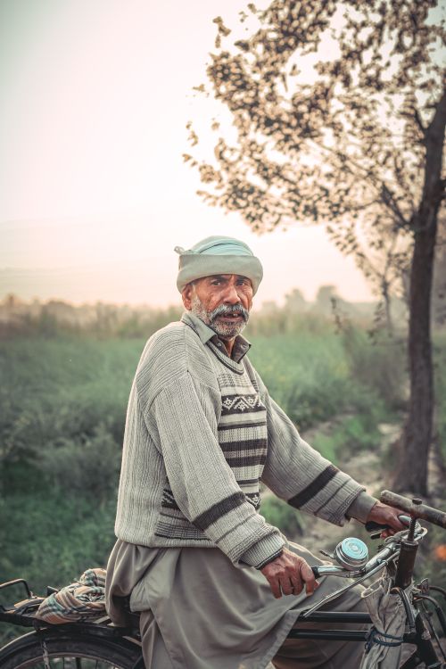 Free An elderly man with a gray sweater rides a bicycle in Kot Sabzal, Punjab, Pakistan. Stock Photo