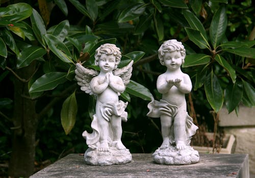 Close-Up Shot of White Angel Figurines on Concrete Surface