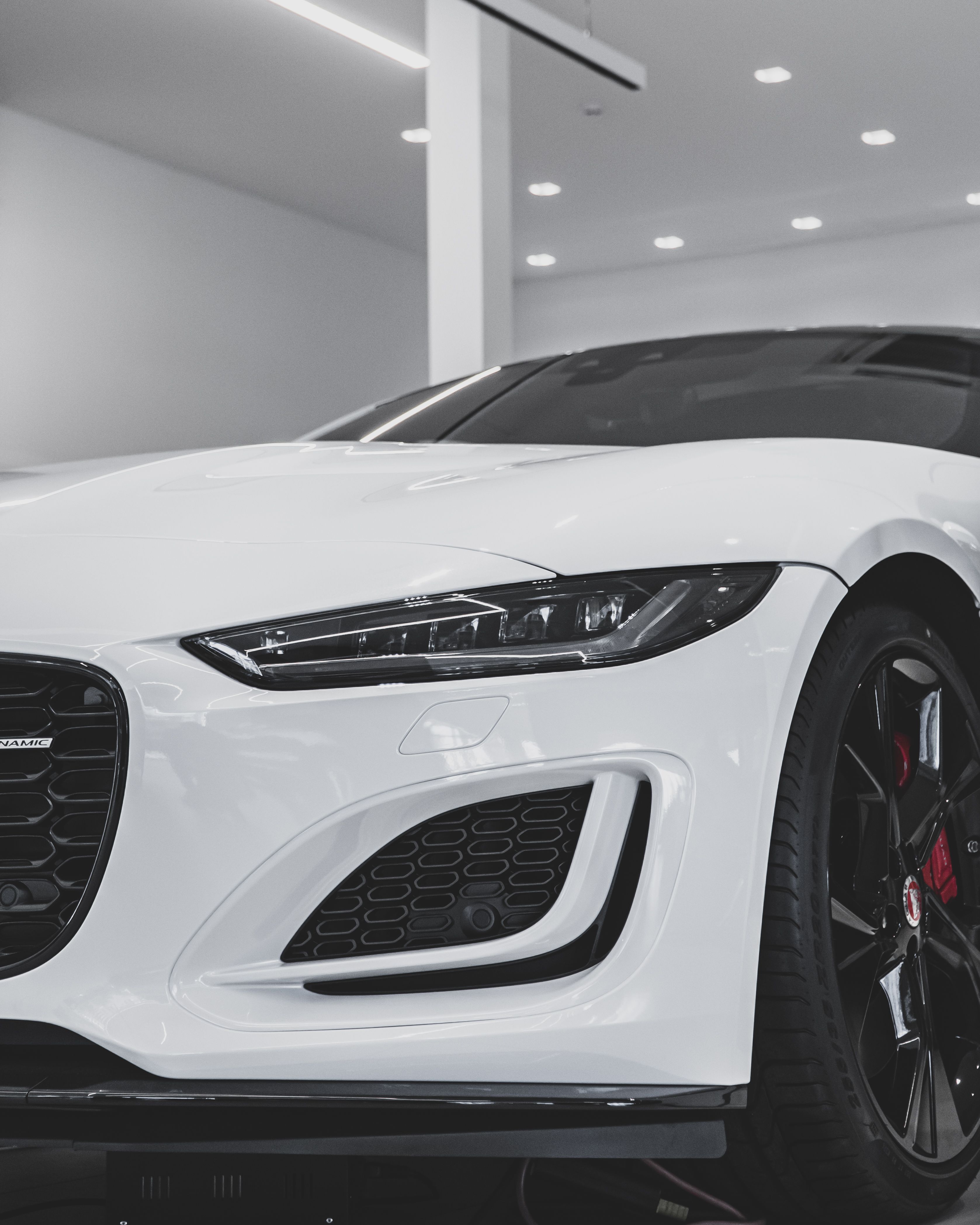 Close-up of a modern white sports car displayed in a showroom setting, highlighting its sleek design.