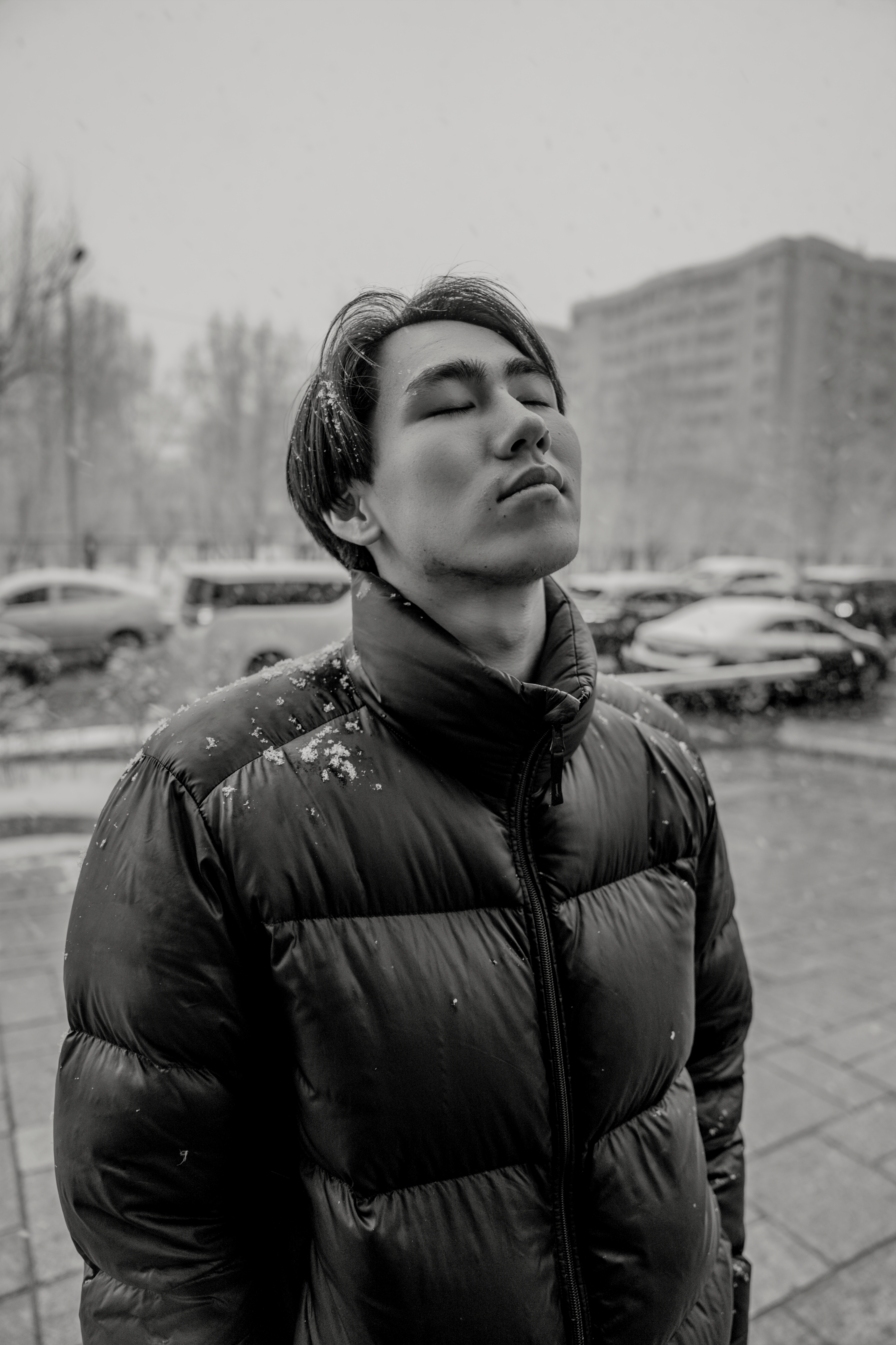 Young person with eyes closed, standing in snow, Ulaanbaatar, Mongolia.