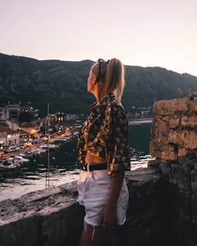 Caucasian woman in stylish outfit enjoying the sunset view over Kotor Bay, Montenegro