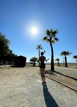 Woman exercising with a jump rope on a bright, sunny beach with palm trees.