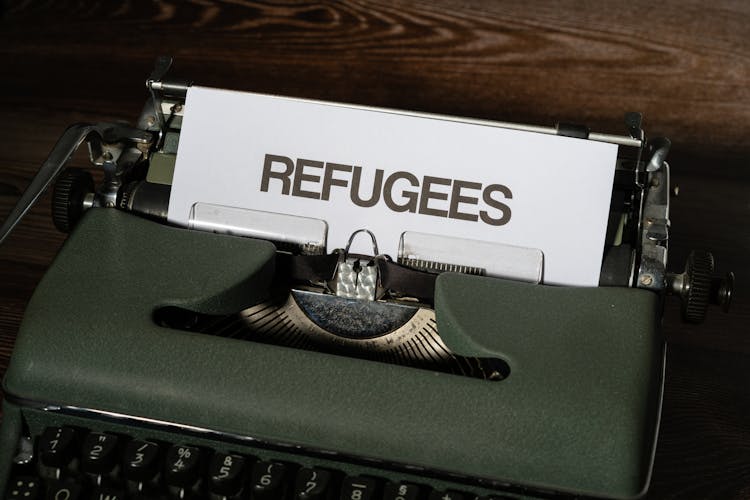 Refugees Word On A White Paper In A Mechanical Typewriter