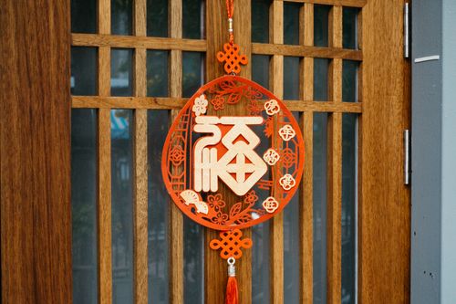 Free Close-up of a red Chinese hanging ornament symbolizing luck, attached to a wooden door. Stock Photo