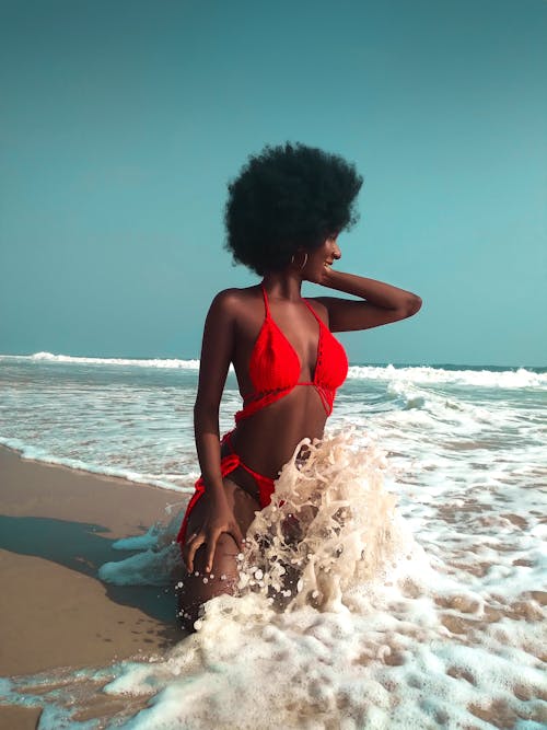 A Woman Kneeling on the Shore of a Beach 