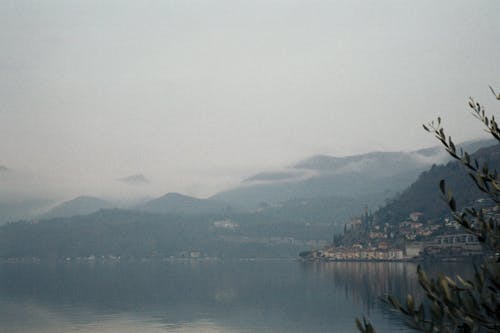 Body of Water Near Mountain on a Foggy Day