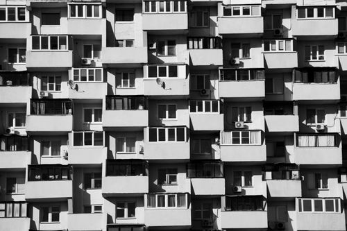 Free Black and white image of a symmetrical apartment building facade with balconies and windows in an urban setting. Stock Photo