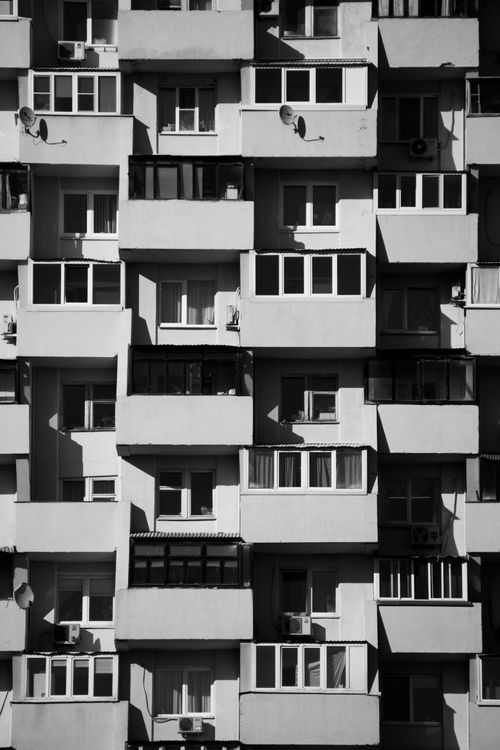 Free A black-and-white image of an apartment building facade with balconies and windows, showcasing modern architecture. Stock Photo
